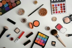 A vibrant collection of makeup and beauty products arranged in a flat lay on a white background.